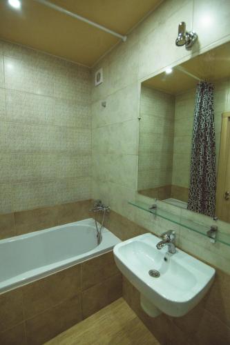 y baño con lavabo, bañera y espejo. en Vip apartmen Harkovskaya, en Sumy