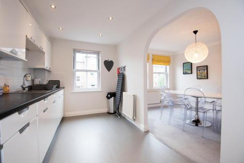 a kitchen with white cabinets and a table with chairs at Dalton Crescent in Durham