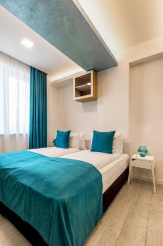a bedroom with a large bed with blue sheets at Mava Apartamente in Constanţa