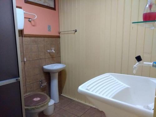 a bathroom with a toilet and a sink and a tub at Apartamento Dois in Caxias do Sul