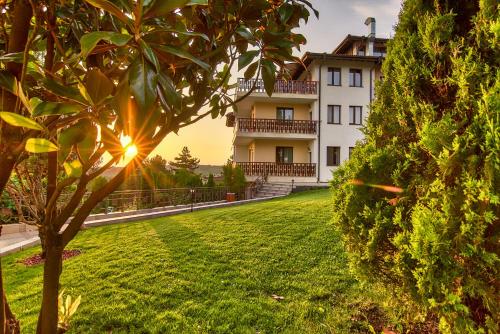 a house with a tree in front of a yard at Park Hotel Arbanassi in Arbanasi