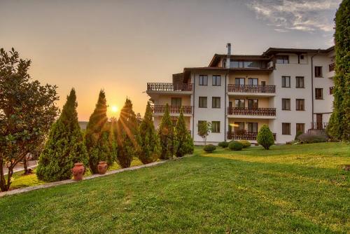 a building with a lawn in front of a sunset at Park Hotel Arbanassi in Arbanasi