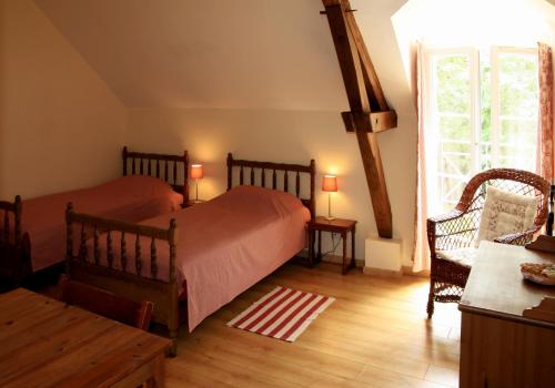 a bedroom with two beds and a table and a window at Gîte du Moulin de Montrésor in Montrésor