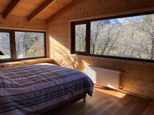 um quarto com uma cama num quarto de madeira com janelas em Chalet Ciprés em Las Trancas