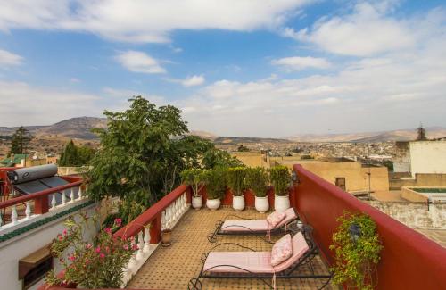 a balcony with chairs and potted plants on a building at Riad Dar Skalli & SPA in Fès