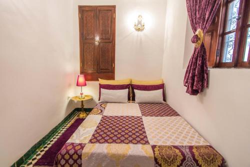 a bedroom with a bed with a quilt on it at Riad Dar Skalli & SPA in Fès