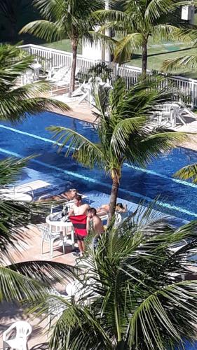 eine Gruppe von Menschen, die an einem Tisch am Pool sitzen in der Unterkunft Tranquilidade e diversão in Mangaratiba