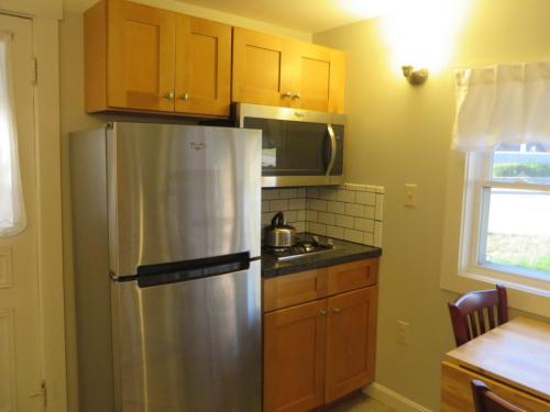 a kitchen with a stainless steel refrigerator and wooden cabinets at Elmwood Motor Court in Old Orchard Beach