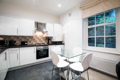 a kitchen with white cabinets and a glass table and chairs at Apartment 2 The Grove in Durham