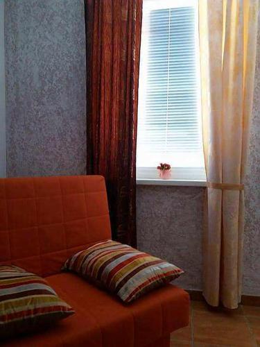 an orange couch sitting in front of a window at Guesthouse Vladimir & Ana in Pančevo