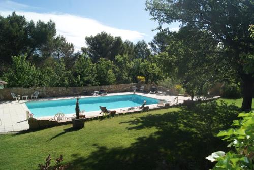 a swimming pool in a yard with chairs and trees at Le Mas des Chênes in Rognes