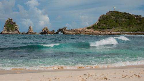 a wave in the ocean next to a beach at Locastudio - Carambole in Sainte-Anne