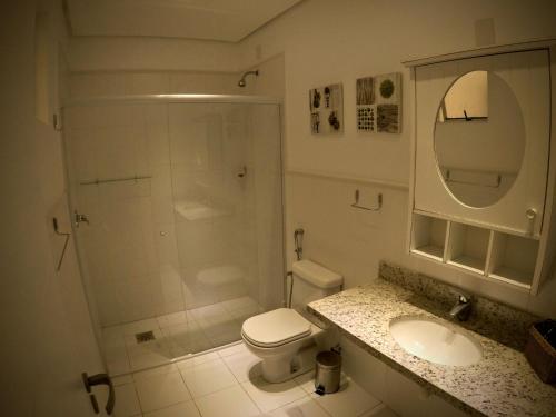 uma casa de banho com um chuveiro, um WC e um lavatório. em Águas do Santinho Apart em Florianópolis