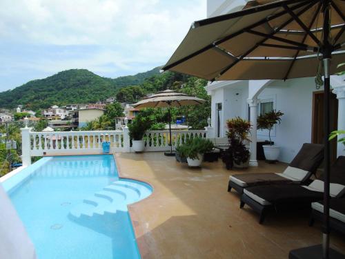 a swimming pool with chairs and an umbrella on a balcony at Taboga Palace SPA Hotel in Taboga