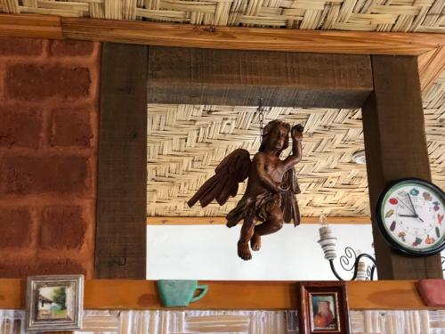 a statue of an angel hanging on a wall next to a clock at Pouso Realeza in Tiradentes