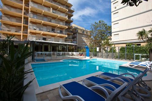 einen Pool mit Stühlen und ein Gebäude in der Unterkunft Hotel Sayonara in San Benedetto del Tronto