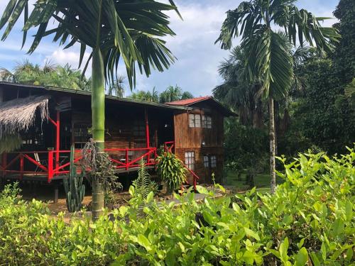 dom z czerwonym płotem przed nim w obiekcie Posada turística Quenari Wii w mieście Mitú