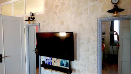 een flatscreen-tv hangend aan een stenen muur bij Le LUMIERE in La Ciotat