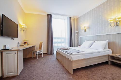 a hotel room with a bed and a desk and a television at AYKUN Hotel by AG Hotels Group in Astana