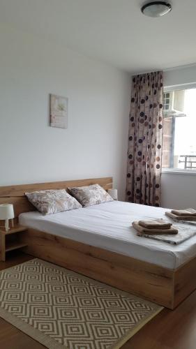 a bedroom with a large wooden bed with a window at GENIKO Apartments in Pomorie