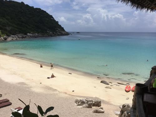 a beach with a group of people in the water at Chabalay Resort in Koh Tao