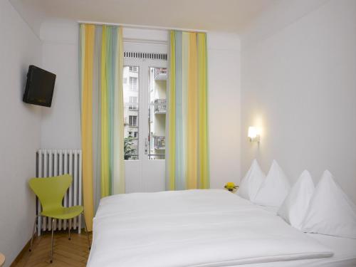 a bedroom with a white bedspread and white pillows at Hotel Marthahaus in Bern
