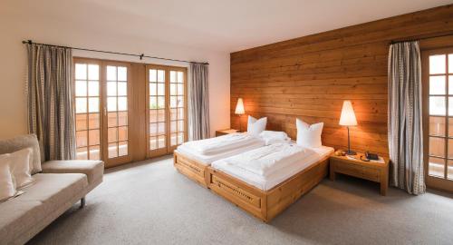 a bedroom with a bed and a couch and windows at Landgasthof "Wilder Mann" in Innsbruck