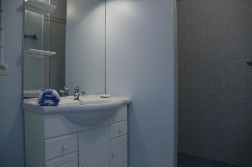 a white bathroom with a sink and a mirror at Hotel Residence Les Alizes in Grand-Village-Plage