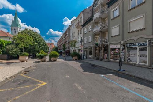 an empty city street with buildings and a church at Főtér Apartman Kaposvár in Kaposvár