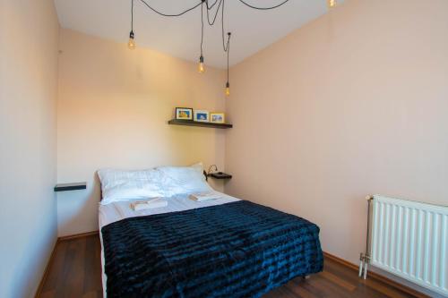 a bedroom with a bed with a blue blanket at Főtér Apartman Kaposvár in Kaposvár