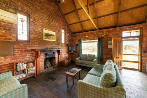 ein Wohnzimmer mit 2 Sofas und einer Ziegelwand in der Unterkunft Grampians Pioneer Cottages in Halls Gap