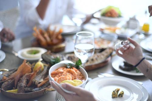 a group of people sitting around a table with food at Miramar Hotel Resort and Spa in Trâblous