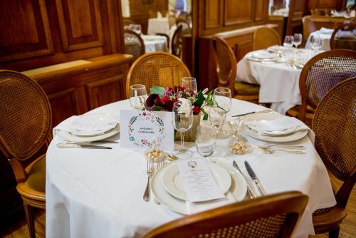 a table with white plates and flowers on it at Grand Hotel Gallia & Londres in Lourdes