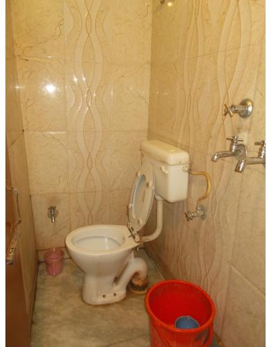 a bathroom with a toilet and a red bucket at Deluxe Stay near ISBT in Rishīkesh