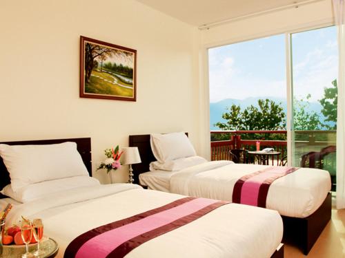 two beds in a room with a balcony at Fueng Fah Riverside Gardens Resort in Mae Rim