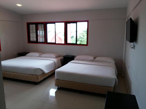 two beds in a room with two windows at KT Chinatown Lodge in Kuala Terengganu