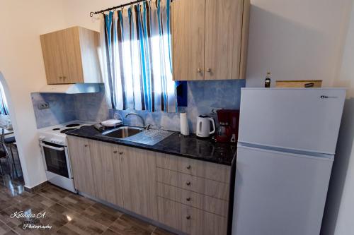 a kitchen with a white refrigerator and a sink at Riva Del Mare in Archangelos