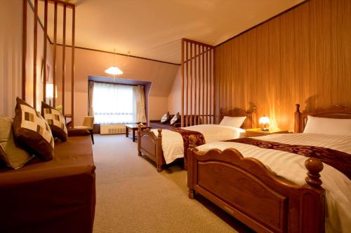 a hotel room with two beds and a couch at Takamiya Hotel Jurin in Zao Onsen