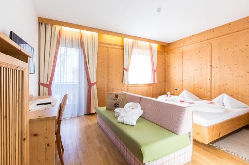 a room with a bed and a desk and a table at Hotel Goldene Rose in Monguelfo