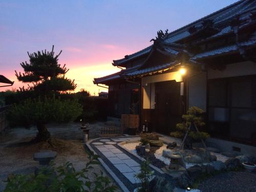 a house with a sunset in the background at しまなみ海道お宿ぽんぽこ in Imabari