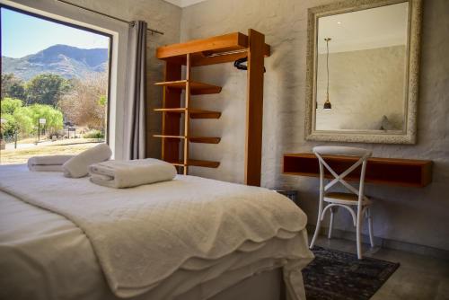 a bedroom with a bed and a mirror and a chair at Birchwood A & B @ Clarens in Clarens