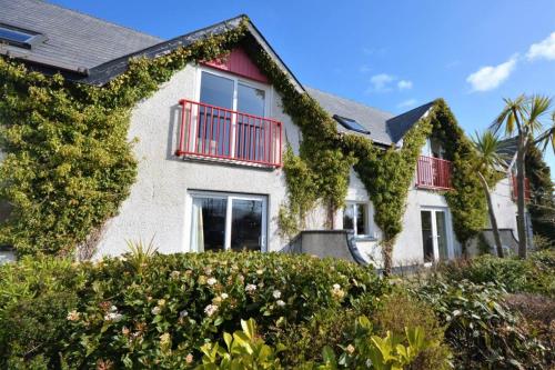 a house covered in ivy with a red balcony at Causeway Coast Apartment in Ballycastle