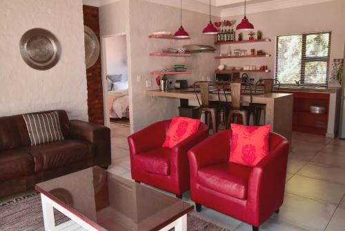 a living room with red chairs and a kitchen at Birchwood A & B @ Clarens in Clarens