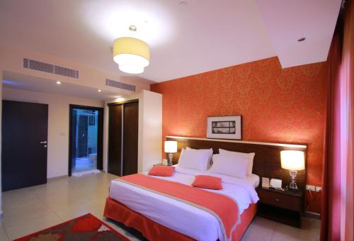 a bedroom with a large bed with an orange wall at City Rose Hotel Suites in Amman