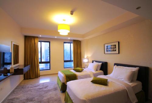 a hotel room with two beds and a television at City Rose Hotel Suites in Amman