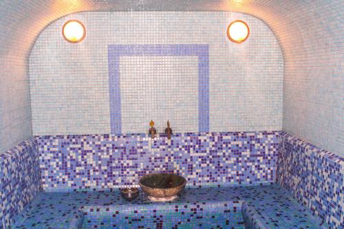 a blue tiled bathroom with a tub with a bowl at Belon Life Hotel in Astana