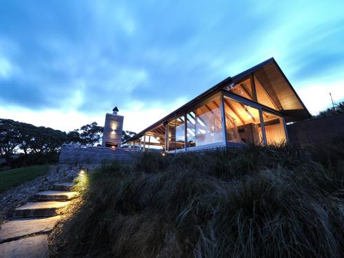 a glass house on a hill with a pathway at The Glasshouse in Whangarei Heads