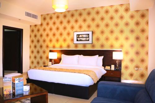 a bedroom with a bed and a blue chair at City Rose Hotel Suites in Amman
