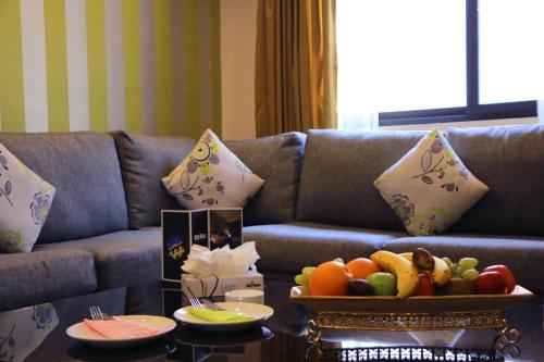 a couch with a table with a bowl of fruit on it at City Rose Hotel Suites in Amman