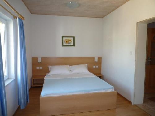 sypialnia z łóżkiem z drewnianym zagłówkiem w obiekcie Apartments Grgic w mieście Novigrad